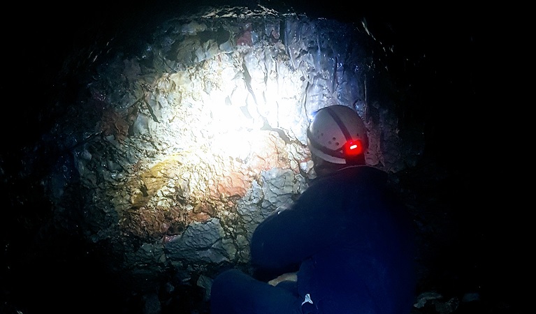 A person looking at a rock structure on a caving tour, Yarangobilly Caves, Kosciuszko National Park. Photo: Teagan Symons/OEH