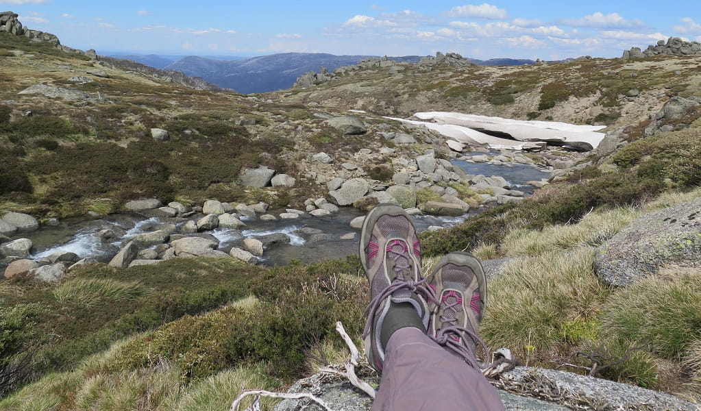 Walker rests to take in the view of a rocky stream surrounded by mountains in Kosciuszko National Park. Photo: Elinor Sheargold &copy; OEH
