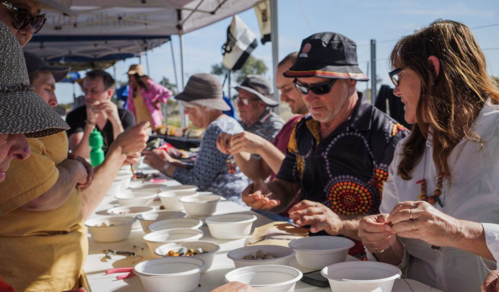 A group of people creating beaded necklaces during an Aboriginal art workshop at Mutawintji cultural festival. Photo: Otis Filley/DCCEEW &copy; DCCEEW