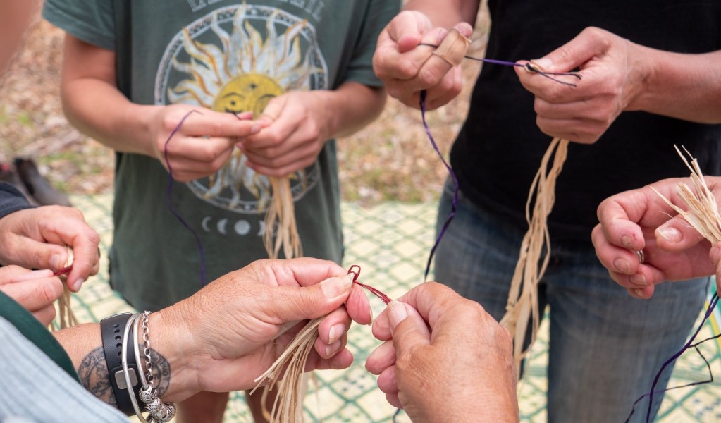 A group of people hand-weaving natural plant fibres at a traditional Aboriginal weaving workshop. Photo: Jessica Taunton/DCCEEW &copy; Jessica Taunton