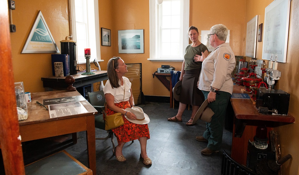 Two visitors listen to a tour guide in the lighthouse keeper's office, Smoky Cape Lighthouse, Hat Head National Park. Credit: Louise Walpole/DCCEEW &copy;DCCEEW