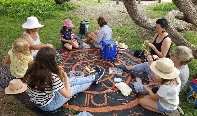 Group of people sitting in a circle doing traditional weaving. Photo: Deidre Martin/OEH