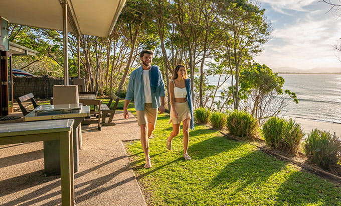 A man and woman walk in front of the verandah at Mildenhall Cottage in Cape Byron State Conservation Area. Photo: John Spencer/DPIE