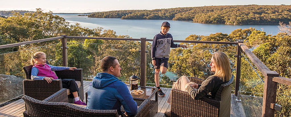 A family relax on the balcony at Hilltop Cottage, Royal National Park. Photo: John Spencer/DPIE