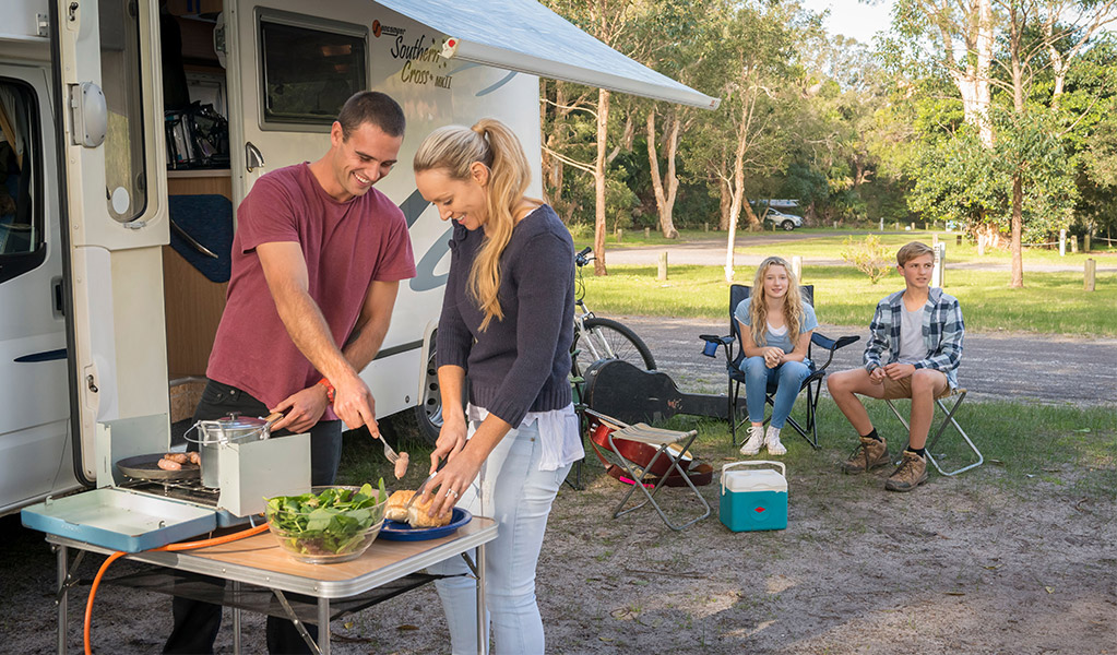 Campers cooking sausages on portable gas burner. Credit: John Spencer © DCCEEW