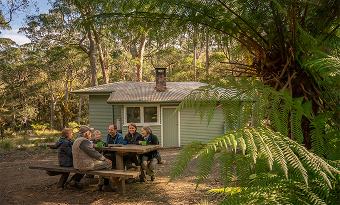 People at a picnic table outside Toms Cabin. Photo: John Spencer &copy; DPE