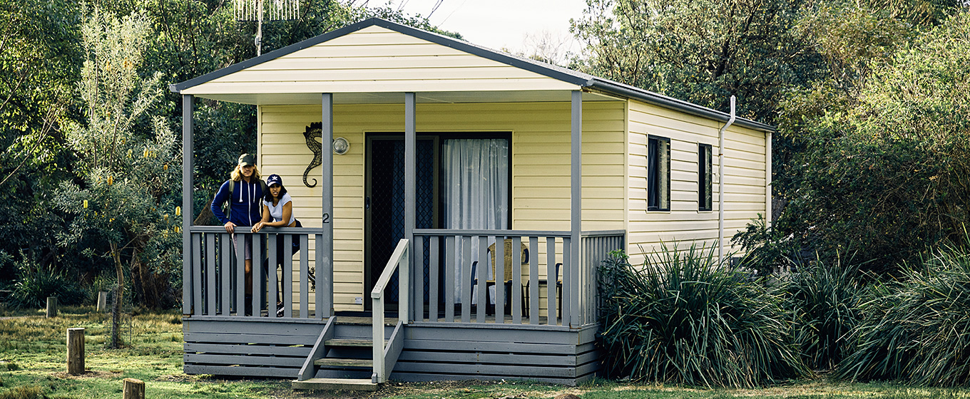 Couple standing on verandah of Pretty Beach cabins in Murramarang National Park. Photo: Melissa Findley/OEH
