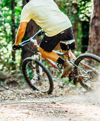 A bike rider moves through the bush, kicking up dirt behind him, in Bald Rock National Park. Photo credit: Jay Black &copy; DPIE
