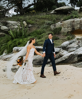 A couple walking on a beach after exchanging wedding vows in Sydney Harbour National Park. Photo: Matthew Horspool &copy; DPE