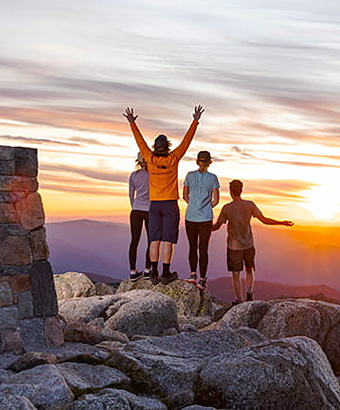 People standing near a rock cairn at the summit of Mount Kosciuszko at sunset. Photo &copy; Thredbo Resort