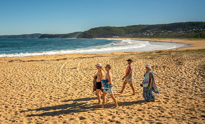A group of people walking along Putty Beach in Bouddi National Park. Photo: John Spencer/DPIE