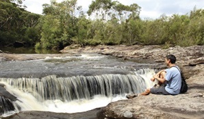 A man sits by a waterfall in Heathcote National Park. Photo: John Yurasek/OEH