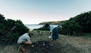 A man and women pick up rubbish at Emily Miller Beach, Murramarang National Park. Photo: Melissa Findley/OEH