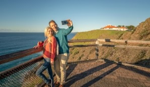 A couple taking a selfie near the Assistant Lighthouse Keepers Cottages in Walgun Cape Byron State Conservation Area. Photo: John Spencer © DCCEEW