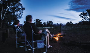 A couple sit by a campfire at Camp Blackman, in Warrumbungle National Park. Photo: Simone Cottrell/OEH