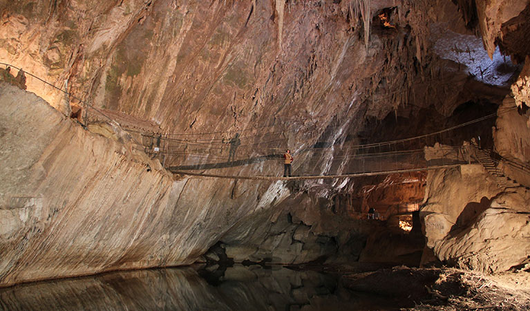 A visitor walks across a swing bridge in Belfry Cave at Abercrombie Karst Conservation Reserve. Photo: Stephen Babka/DPIE