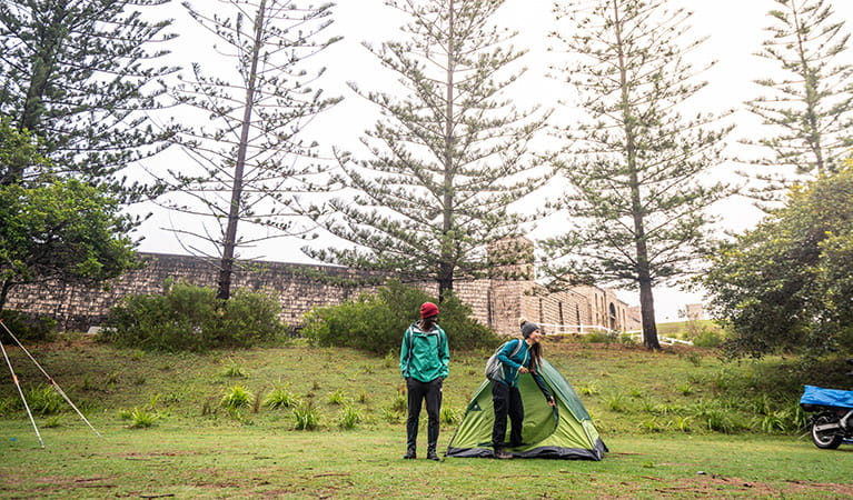 Campers zipping up their tent in Trial Bay Gaol campground, Arakoon National Park. Photo: Rob Mulally/DPIE