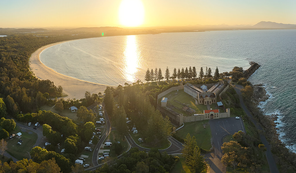 Aerial view of Trial Bay Gaol campground and the ocean at sunset. Credit: Glen Ellis &copy; DCCEEW