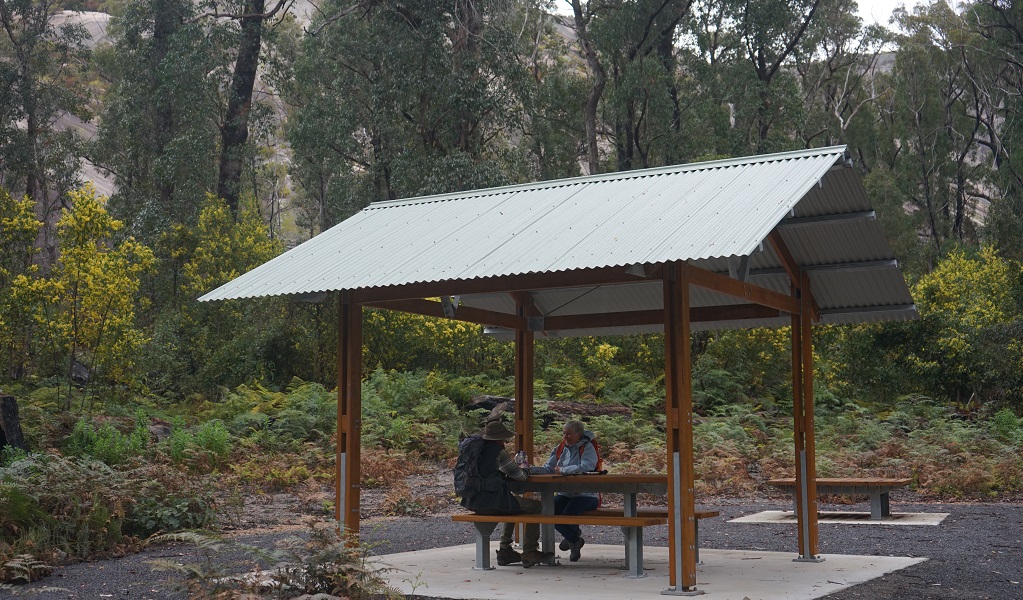 Two walkers rest at a picnic bench at the base of Bald rock in Bald Rock National Park. Photo: Christopher Ghirardello/DPE