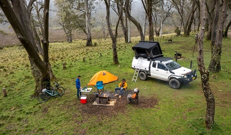 Campers around a wood barbecue next to a tent and a 4WD with a car tent in Polblue campground and picnic area. Credit: John Spencer/DCCEEW  &copy; DCCEEW