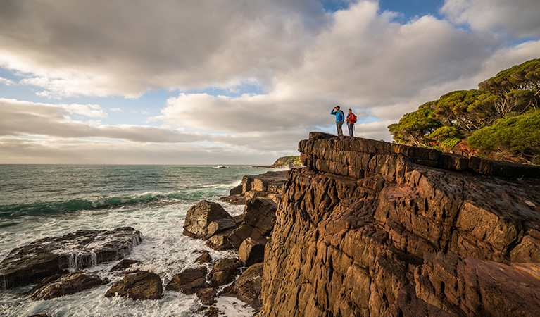 Bushwalkers on cliffside, Bittangabee campground, Beowa National Park. Photo: John Spencer/OEH