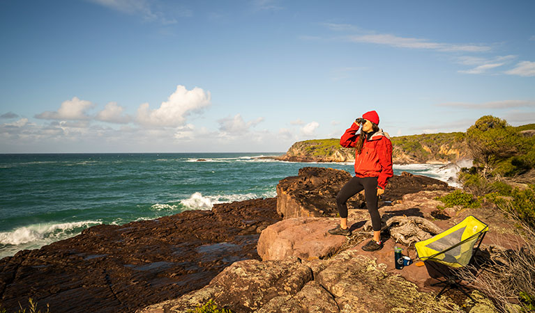 Woman whale watching from the rocks near Bittangabee Bay in Beowa National Park. Photo: John Spencer &copy; OEH