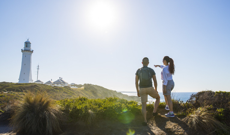 A couple admires Green Cape Lightstation from a distance in Beowa National Park. Photo: Tim Clark/DNSW