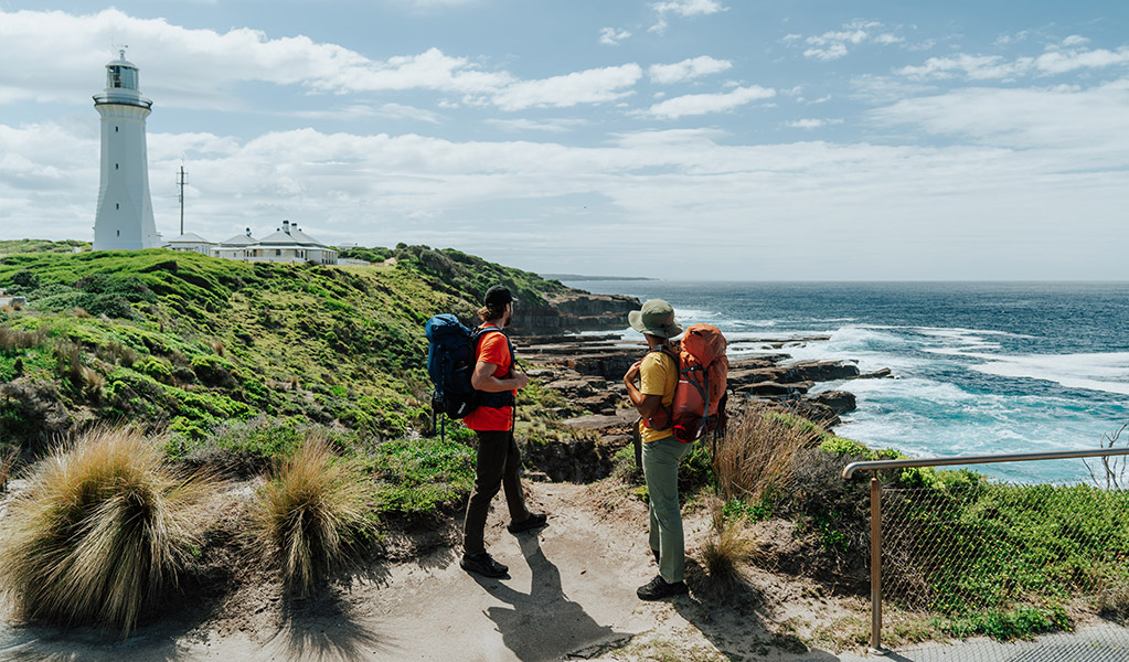 Hikers at Green Cape lookout with the lighthouse in the distance. Credit: Remy Brand/DCCEEW &copy; Remy Brand