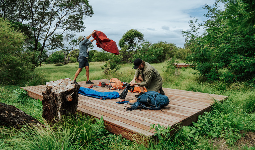 Hikers setting up a tent on a hardwood tent platform at Mowarry campground. Credit: Remy Brand/DCCEEW &copy; Remy Brand