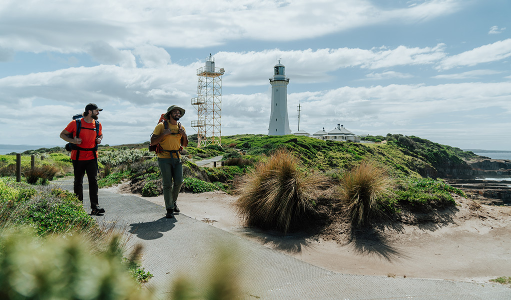 Hikers finishing the Light to Light Walk, Green Cape Lighthouse in the distance. Credit: Remy Brand/DCCEEW &copy; Remy Brand