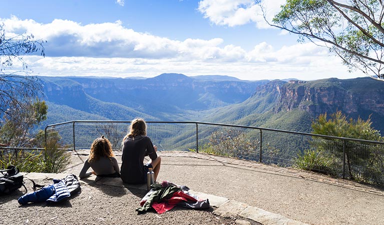 A couple sit at Evans lookout, Blue Mountains National Park. Photo: Simone Cottrell &copy; DPE