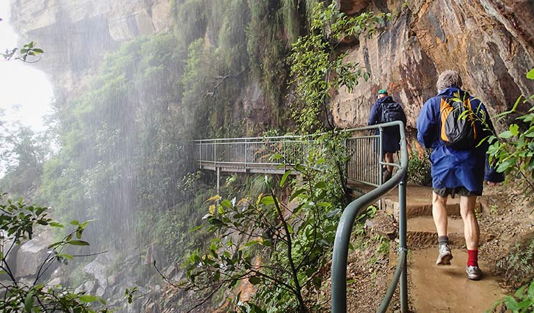 Walkers pass under a waterfall on National Pass, Blue Mountains National Park. Photo: Aine Gliddon/OEH