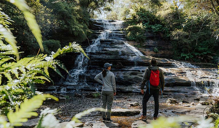 2 walkers admiring the site of Katoomba Falls from the pool at its base, Greater Blue Mountains Heritage Area. Photo: Remy Brand &copy; Remy Brand