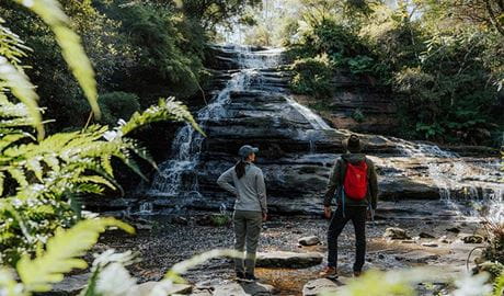2 walkers admiring the site of Katoomba Falls from the pool at its base, Greater Blue Mountains Heritage Area. Photo: Remy Brand &copy; Remy Brand