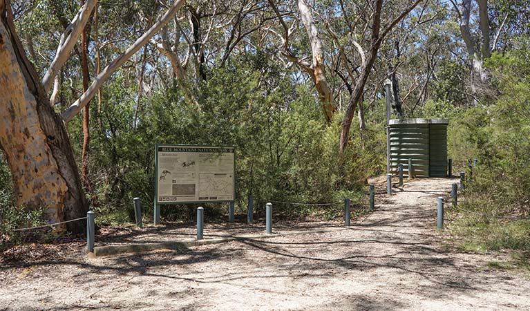 Gravel path past sign to non-flush toilet, Ingar campground, Blue Mountains National Park. Photo: Stephen Alton/OEH