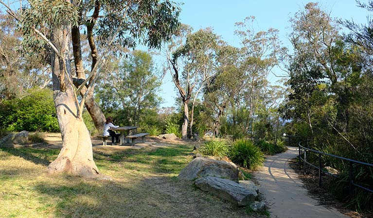 A woman sits at a picnic table at Wentworth Falls picnic area, Blue Mountains National Park. Photo: E Sheargold/OEH.