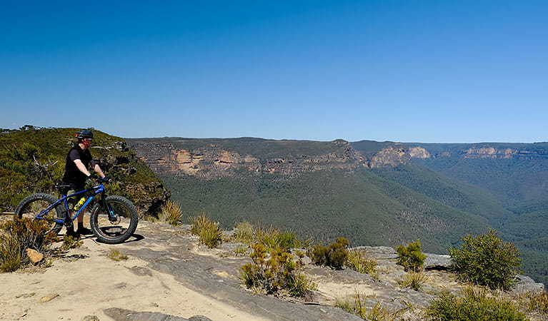 A bike rider and views on Mount Banks Road trail, Blue Mountains National Park. Photo: E Sheargold/OEH.