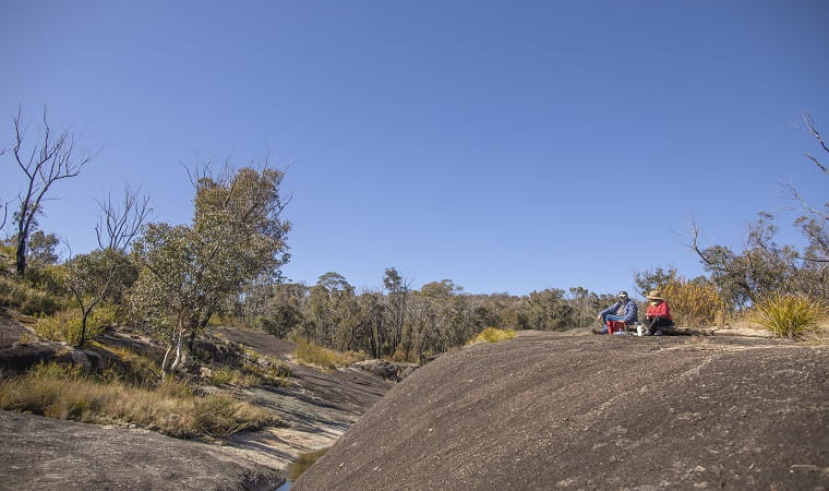 Visitors sitting on the granite rock formations at Morgans Gully picnic area. Photo: Joshua J  Smith &copy; DPE
