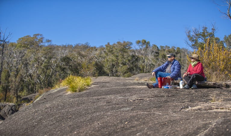 Visitors sitting on the granite rock formations at Morgans Gully picnic area. Photo: Joshua J &copy; Smith DPE