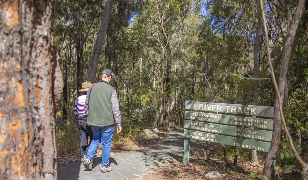 Two people walking past directional signage on River walk in Boonoo Boonoo National Park. Photo: Joshua Smith &copy; DPE