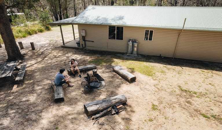 Guests sitting on logs around the firepit at Robinsons Cabin. Photo credit: Harrison Candlin &copy; Harrison Candlin