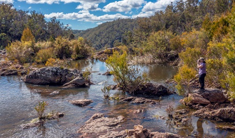 Person looking out over rockpools in Boonoo Boonoo National Park. Photo: Joshua J Smith, &copy; DCCEEW