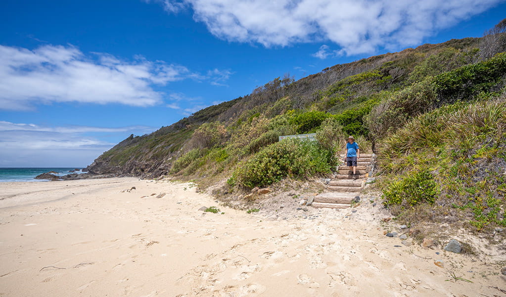 A bushwalker arriving at the beach along Booti walking track in Booti Booti National Park. Credit: John Spencer &copy; DPE