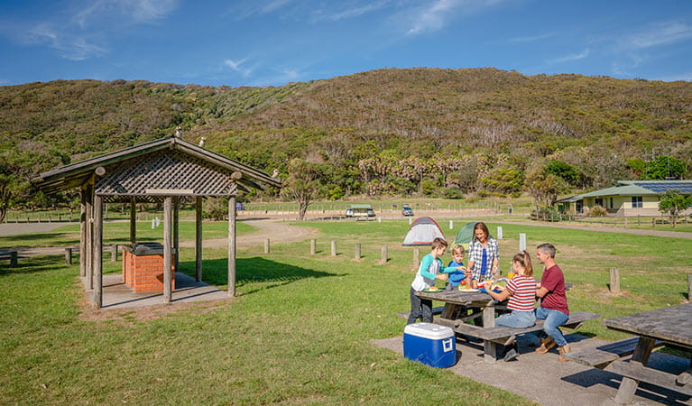 A family at a picnic table at The Ruins picnic area, Booti Booti National Park. Photo credit: John Spencer &copy; DPIE