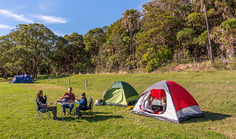 People sitting beside two tents at The Ruins campground in Booti Booti National Park. Photo credit: John Spencer & copy; DPIE