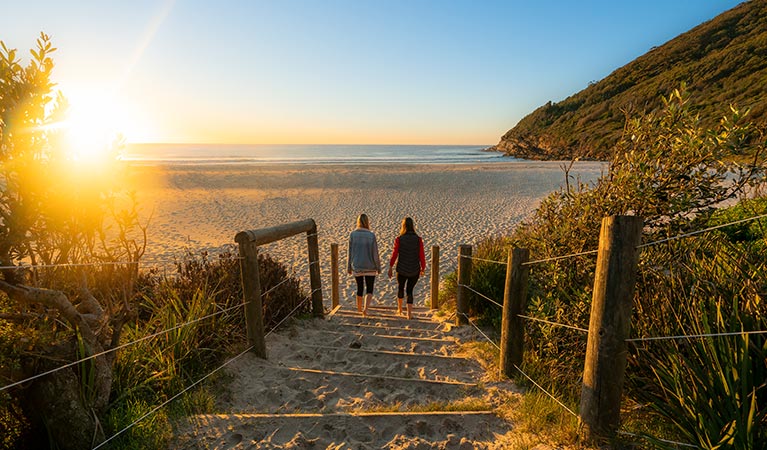 Two women walk towards a beach at sunrise, Booti Booti National Park. Photo credit: John Spencer &copy; DPIE