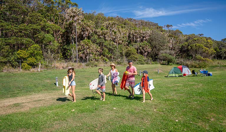 A family walks from their tents to the beach, at The Ruins campground in Booti Booti National Park. Photo credit: John Spencer &copy; DPIE