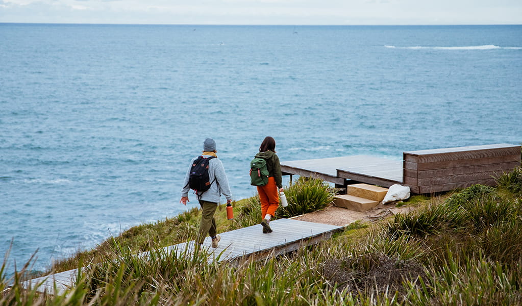 Two walkers approaching an impressive lookout with ocean views on Bouddi coastal walk. Photo: Jared Lyons &copy; DPE