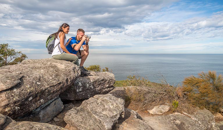 Bushwalkers rest on some rocks overlooking the ocean on Bullimah Spur track. Photo: John Spencer &copy; OEH