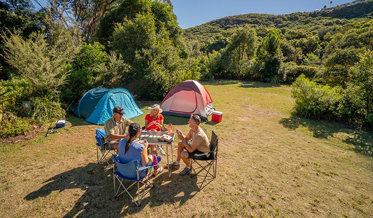 Campers sitting and playing cards at Putty Beach campground. Photo: John Spencer/DPIE